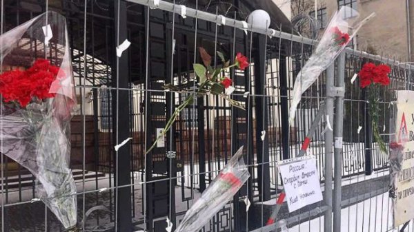 Украинцы несут цветы и свечи к зданию посольства России в Киеве